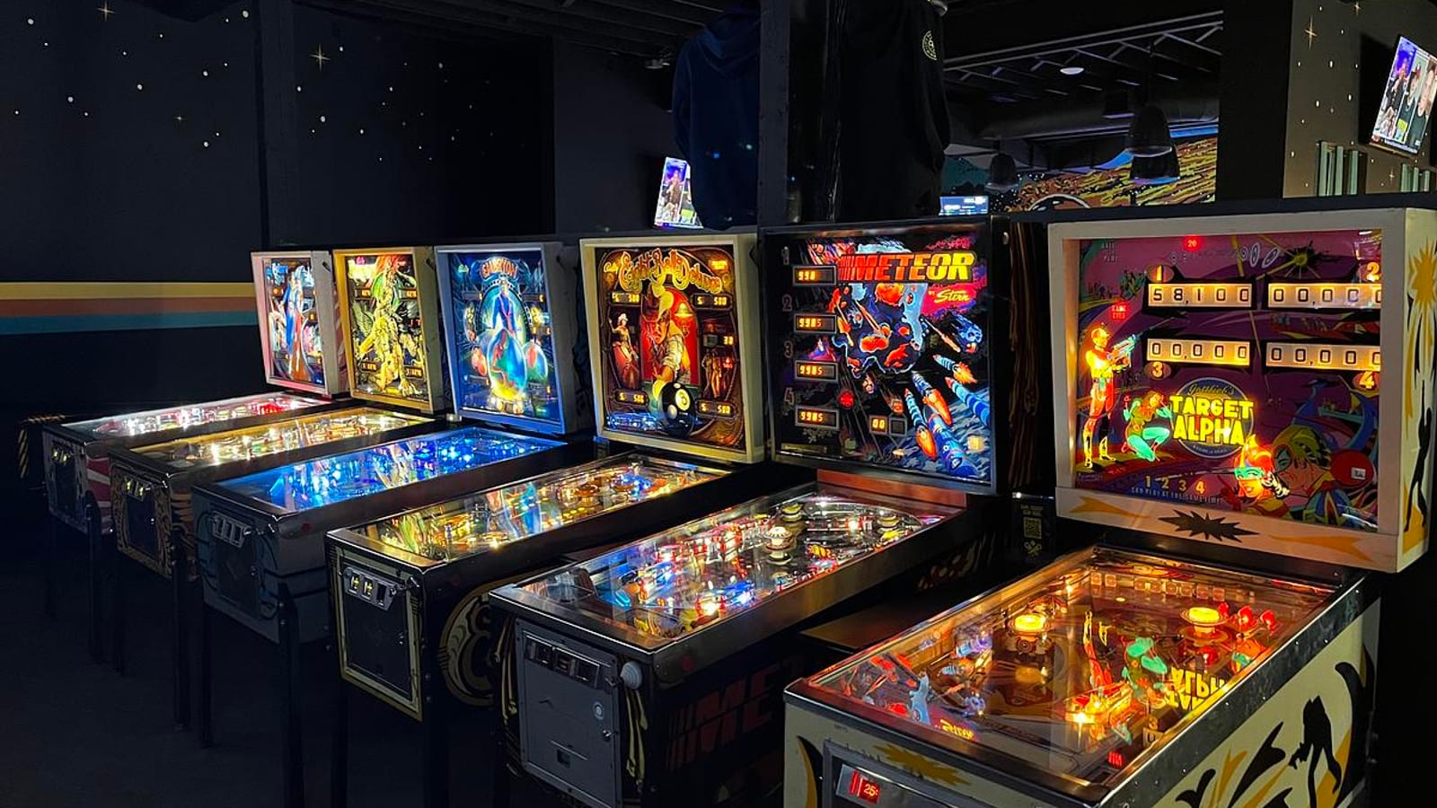 Row of pinball machines lit up inside LITT Pinball Bar in Minneapolis